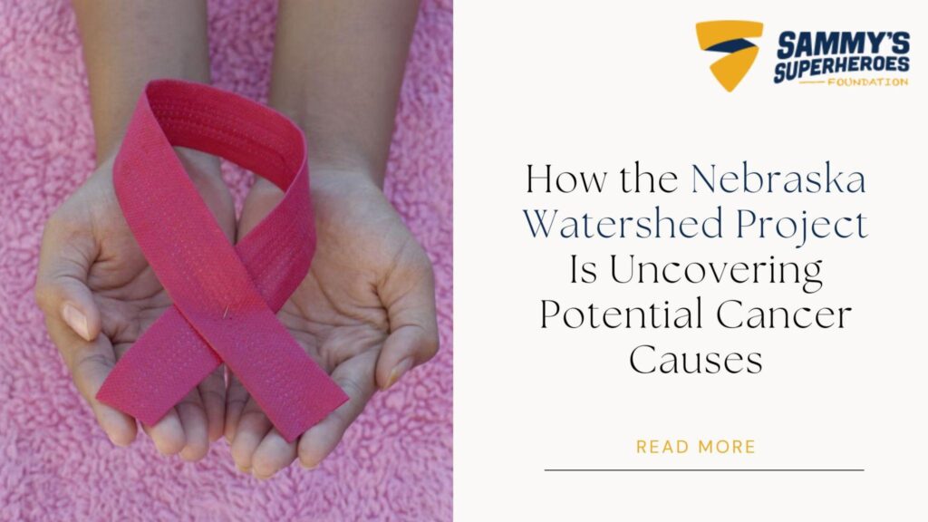 Hands holding a pink cancer awareness ribbon beside text reading “How the Nebraska Watershed Project Is Uncovering Potential Cancer Causes,” representing pediatric cancer research and awareness